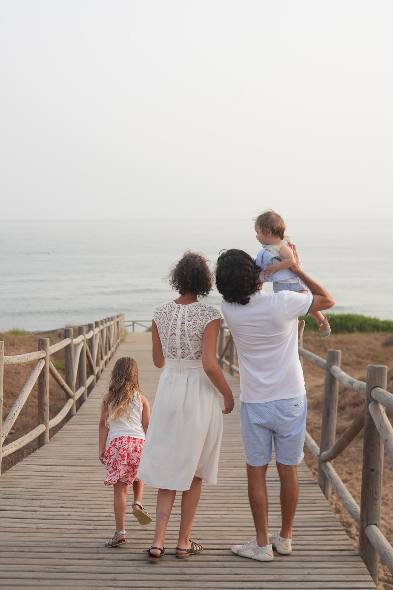 Family walking on a boardwalk to the sea